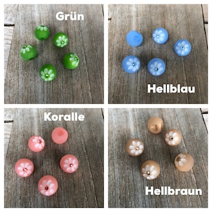 Puede incluir: Surtido de seis botones de vidrio con diseños de flores blancas. Los botones son de cuatro colores: verde, azul claro, coral y marrón claro. Los botones están dispuestos en cuatro grupos, cada grupo etiquetado con el color de los botones de ese grupo.