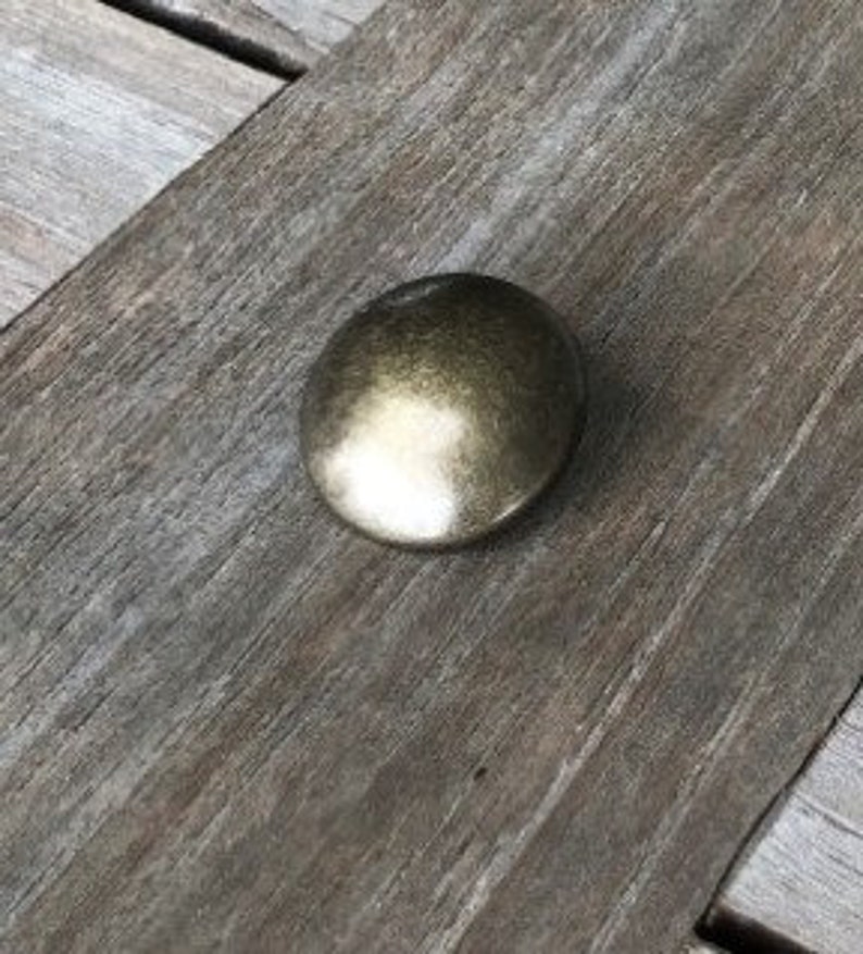 Peut inclure: Un bouton rond en m&eacute;tal de couleur or antique avec une surface lisse l&eacute;g&egrave;rement bomb&eacute;e.