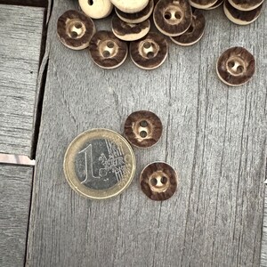Peut inclure: Un tas de boutons bruns et blancs avec un motif brun et blanc. Il y a une pi&egrave;ce de 1 euro dans l'image.