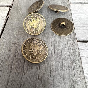 Può includere: Cinque bottoni antichi color oro con un designo in rilievo di un'aquila bicipite e il testo "1 FL" su ogni bottone.