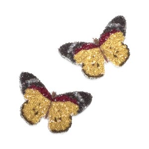 Peut inclure: Deux appliques de papillon en strass avec un corps jaune, des accents rouges et des ailes grises.