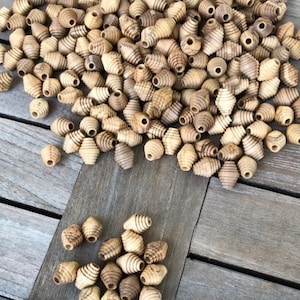 May include: A large pile of wooden beads with a spiral design. The beads are a light brown color and have a natural wood finish.