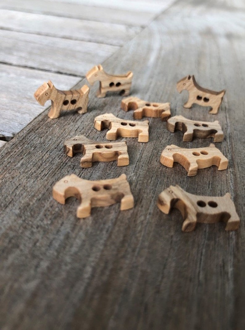 Peut inclure: Une collection de boutons en bois en forme de chiens. Les boutons sont de couleur brun clair avec un grain de bois brun fonc&eacute;.