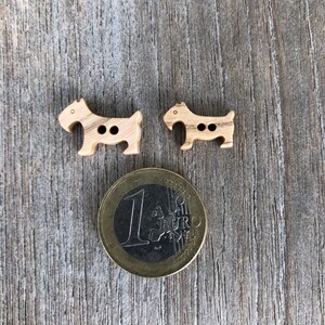 Peut inclure: Deux boutons en bois en forme de chien. Les boutons sont bruns et ont deux trous chacun. Une pi&egrave;ce d'un euro est incluse pour r&eacute;f&eacute;rence de taille.