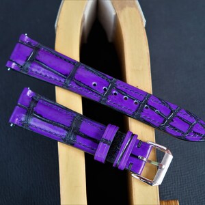 Puede incluir: Dos correas de reloj moradas con estampado de cocodrilo. Una correa tiene una hebilla negra y la otra una hebilla plateada.