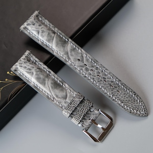 Puede incluir: Dos correas de reloj de cuero gris con un patrón texturizado. Las correas tienen una hebilla plateada.