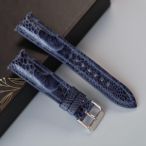 Puede incluir: Dos correas de reloj de cuero azul con un patrón texturizado. Las correas tienen hebillas plateadas.