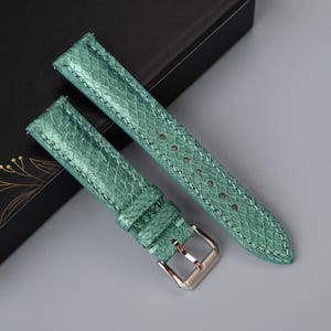 Puede incluir: Dos correas de reloj verdes de cuero con un patrón texturizado. Las correas tienen una hebilla plateada.