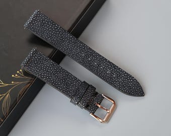 May include: Two gray leather watch straps with a textured surface. One strap has a gold buckle.