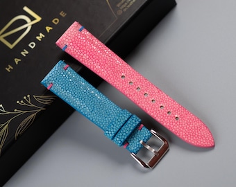 May include: Two watch straps made of stingray leather. One strap is pink and the other is blue. Both straps have a contrasting blue stitching.