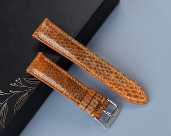 Könnte beinhalten: Zwei braune Lederarmbänder mit einem strukturierten Muster. Die Armbänder haben ein goldfarbenes Nähtdetail und eine silberne Schnalle.