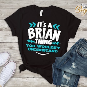 May include: Black t-shirt with white text that reads "It's a Brian thing you wouldn't understand". The text is surrounded by blue wavy lines and arrows.