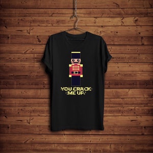 May include: Black t-shirt with a pixelated illustration of a nutcracker soldier and the text "YOU CRACK ME UP".