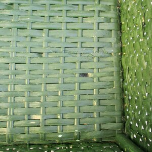Op de afbeelding: Groene geweven rieten stoelzitting met een geweven patroon. De zitting is gemaakt van natuurlijke materialen en heeft een rustieke uitstraling.