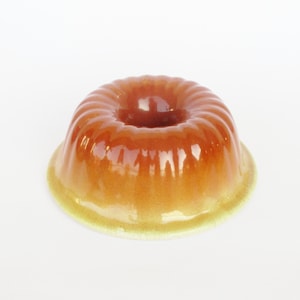 May include: A brown glazed ceramic bundt cake pan with a fluted design. The pan is empty and has a glossy finish.