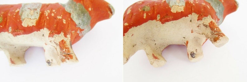 May include: A small, hand-painted, ceramic cow figurine with a white body and orange and gray markings. The cow is standing on all four legs.