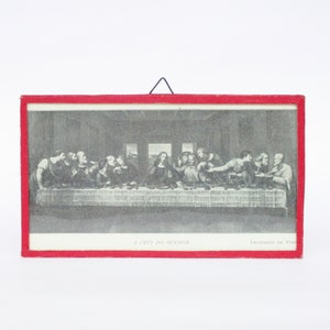 May include: A black and white framed print of Leonardo da Vinci's The Last Supper. The print is in a red frame with a black hanger.