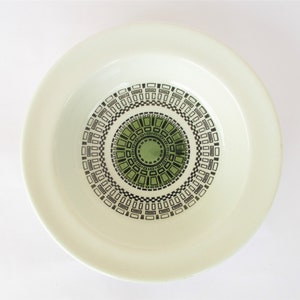 May include: A white ceramic bowl with a green and black geometric design. The design features concentric circles of squares and rectangles.