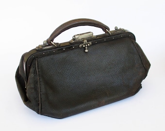 Puede incluir: Un bolso de médico vintage de cuero negro con cierre y asa de metal.