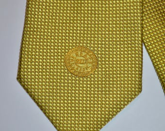 May include: A yellow patterned silk tie with a gold circular emblem featuring the text "V.I.P." in the center.