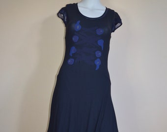 Könnte beinhalten: Ein dunkelblaues, knielanges Kleid mit einer lockeren, fließenden Silhouette. Das Kleid hat kurze Ärmel und ein einzigartiges Design mit blauen und violetten abstrakten Formen auf der Vorderseite.