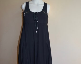Könnte beinhalten: Ein schwarzes, ärmelloses Kleid mit einem Schnürdetail am Ausschnitt und zwei Taschen auf der Vorderseite.