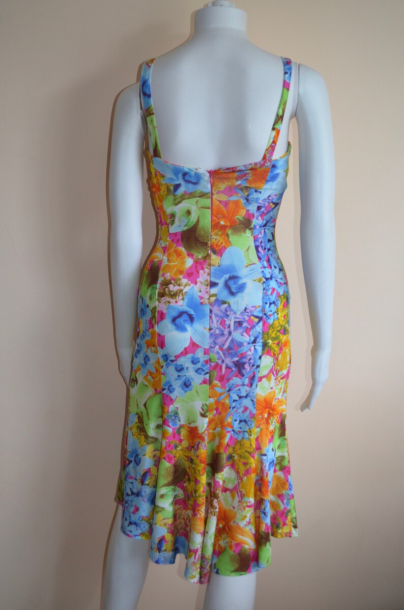 Puede incluir: Un vestido sin mangas con estampado floral en tonos rosa, azul, verde, amarillo y naranja. El vestido tiene un corpi&ntilde;o ajustado y una falda fluida.