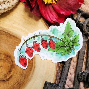 May include: A watercolor sticker featuring a vine with red heart-shaped flowers. The vine is green with leaves and the hearts are a vibrant red. The sticker is on a wooden background.