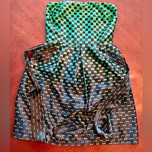 Puede incluir: Vestido sin tirantes con un estampado geom&eacute;trico negro y verde. El vestido presenta un corpi&ntilde;o ajustado y una falda acampanada. La tela tiene un aspecto brillante. El vestido es un minivestido.