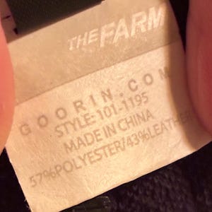 May include: Close-up of a tag with the text "THE FARM" at the top. Below, the tag reads "GOORIN.COM STYLE: 101-1195 MADE IN CHINA 57% POLYESTER/43% LEATHER."