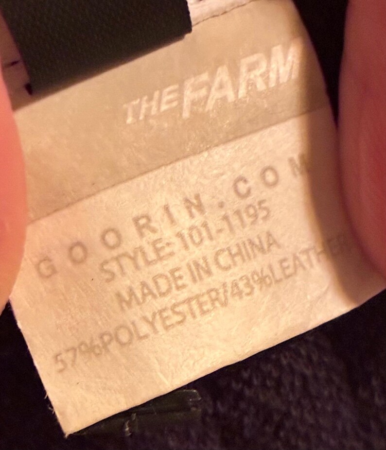 May include: Close-up of a tag with the text "THE FARM" at the top. Below, the tag reads "GOORIN.COM STYLE: 101-1195 MADE IN CHINA 57% POLYESTER/43% LEATHER."