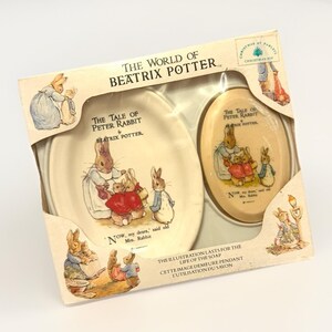 Puede incluir: Un juego en caja con ilustraciones de "The Tale of Peter Rabbit" de Beatrix Potter. El juego incluye un plato y un jabón ovalado, ambos decorados con encantadores personajes de conejos al estilo vintage. La caja dice "Christmas at Partley".