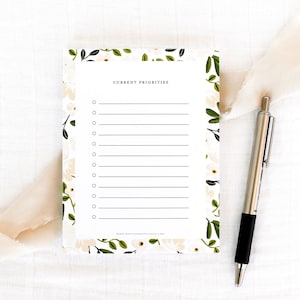 May include: A white notepad with a floral border and the text "CURRENT PRIORITIES" at the top. The notepad has 12 lines for writing.