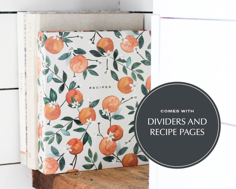 May include: A white recipe binder with a floral pattern of orange blossoms and oranges. The binder has the word "RECIPES" printed on the front. The binder comes with dividers and recipe pages.