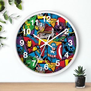 May include: A white round clock with a colorful design featuring various Marvel superheroes, including Iron Man, Captain America, Thor, Hulk, and Spider-Man. The clock face has black numbers and hands. The design includes comic book-style speech bubbles with phrases like "ZWHUMP!" and "FOR ASGAAAARD!"