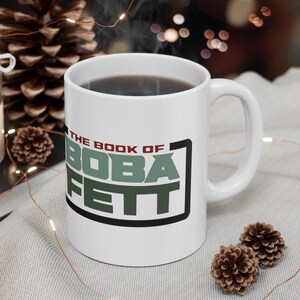 May include: White ceramic mug with a black and green graphic that says "The Book of Boba Fett".