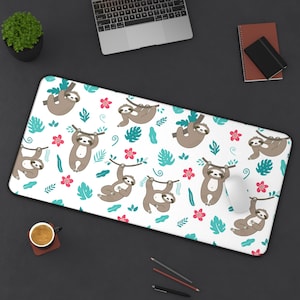 May include: White desk mat with a repeating pattern of sloths hanging from branches with pink flowers and green leaves.