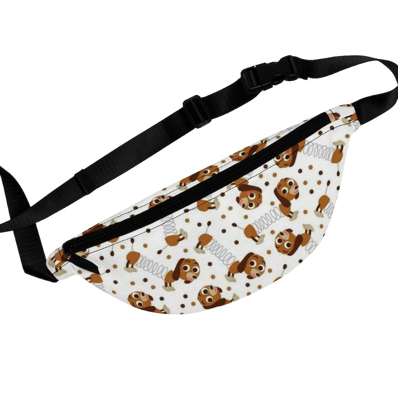 May include: A white fanny pack with a black adjustable strap. The fanny pack has a repeating pattern of brown cartoon dogs with springs on their tails and brown dots.