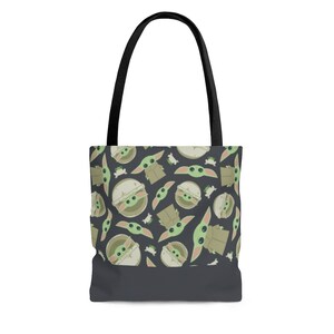 Puede incluir: Una bolsa de mano de color gris oscuro con asas negras presenta un patr&oacute;n repetido de personajes de dibujos animados verdes y marrones con ojos grandes.