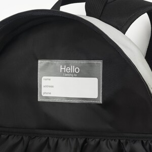 May include: Black backpack with a clear plastic name tag that says "Hello I belong to" with spaces for name, address, and phone number.