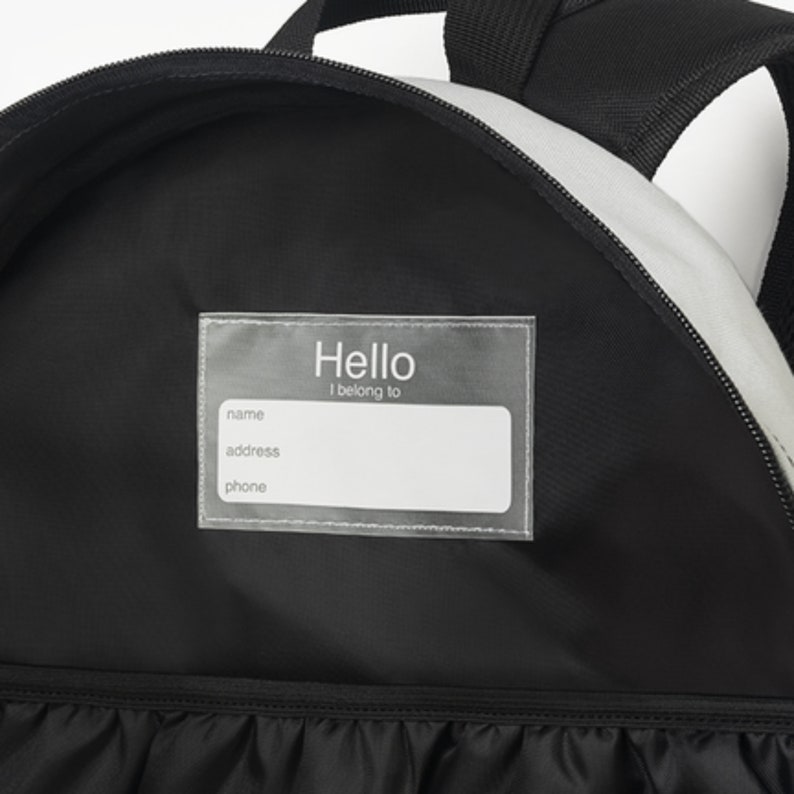 May include: Black backpack with a clear plastic name tag that says "Hello I belong to" with spaces for name, address, and phone number.