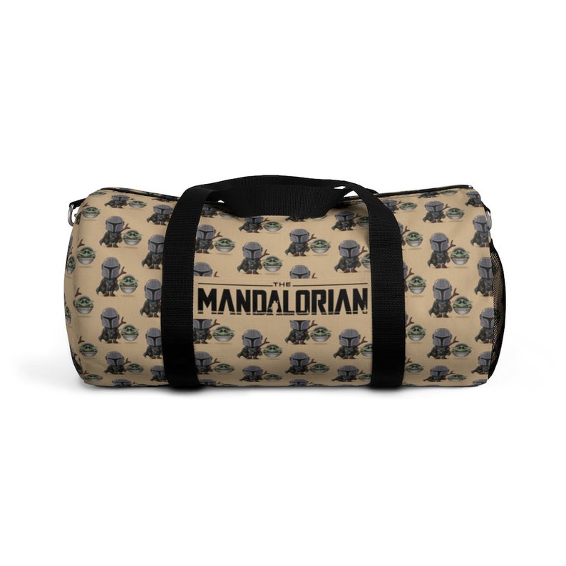 Puede incluir: Una bolsa de lona de color beige con correas negras y un patr&oacute;n repetido de un peque&ntilde;o personaje alien&iacute;gena verde que sostiene un peque&ntilde;o personaje gris. La bolsa tiene el texto "THE MANDALORIAN" impreso en negro en la parte delantera.