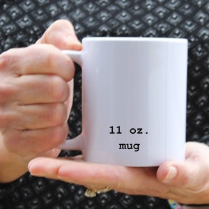 May include: White ceramic mug with a black inscription that reads "11 oz. mug".