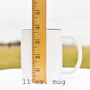 May include: White ceramic 11 oz. mug with a black rim and handle. The mug is next to a wooden ruler.