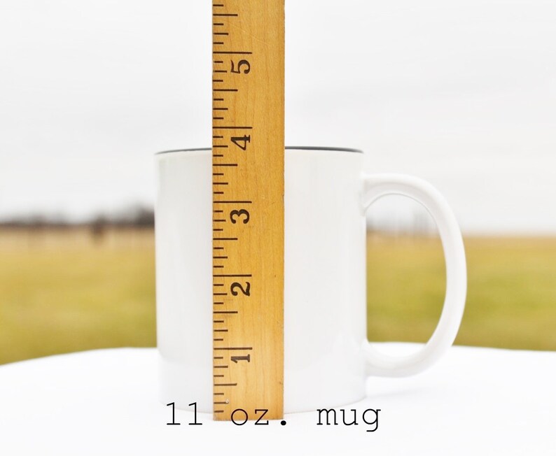 May include: White ceramic 11 oz. mug with a black rim and handle. The mug is next to a wooden ruler.