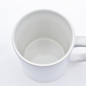 May include: A white ceramic mug with a rounded handle. The mug is empty and ready to be filled with a hot beverage.