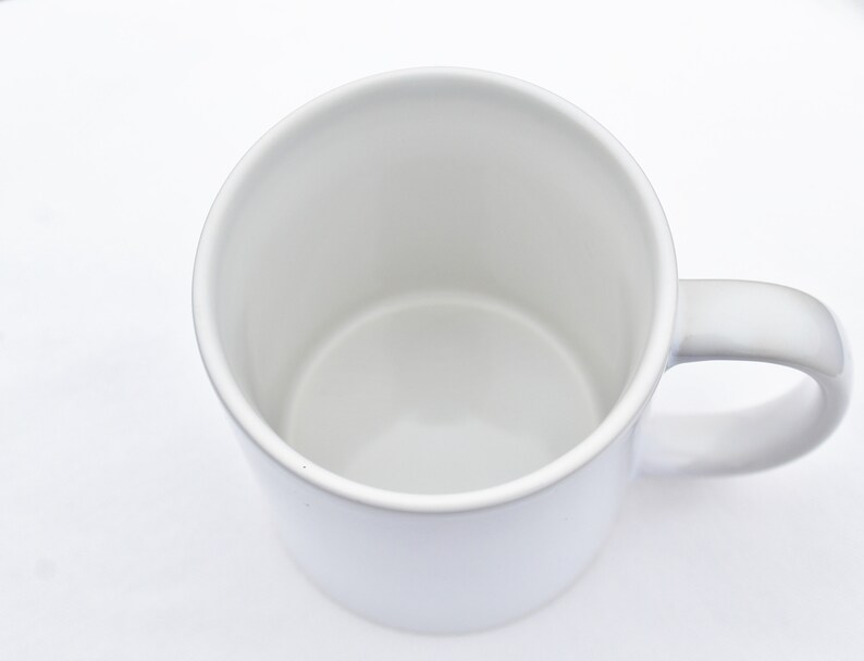 May include: A white ceramic mug with a rounded handle. The mug is empty and ready to be filled with a hot beverage.