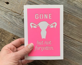 May include: A pink card with a white silhouette of a uterus and the text "GONE but not forgotten".