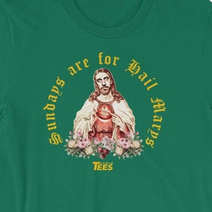 May include: A green t-shirt with a gold graphic of Jesus with the text "Sundays are for Hail Marys" and "TEES" below the graphic.