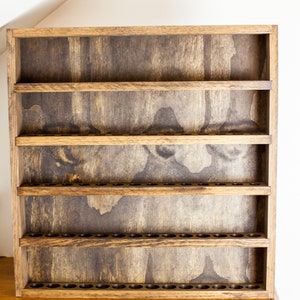 May include: A wooden shelf unit with five shelves and a row of small holes along the bottom of each shelf. The shelves are stained a dark brown color.